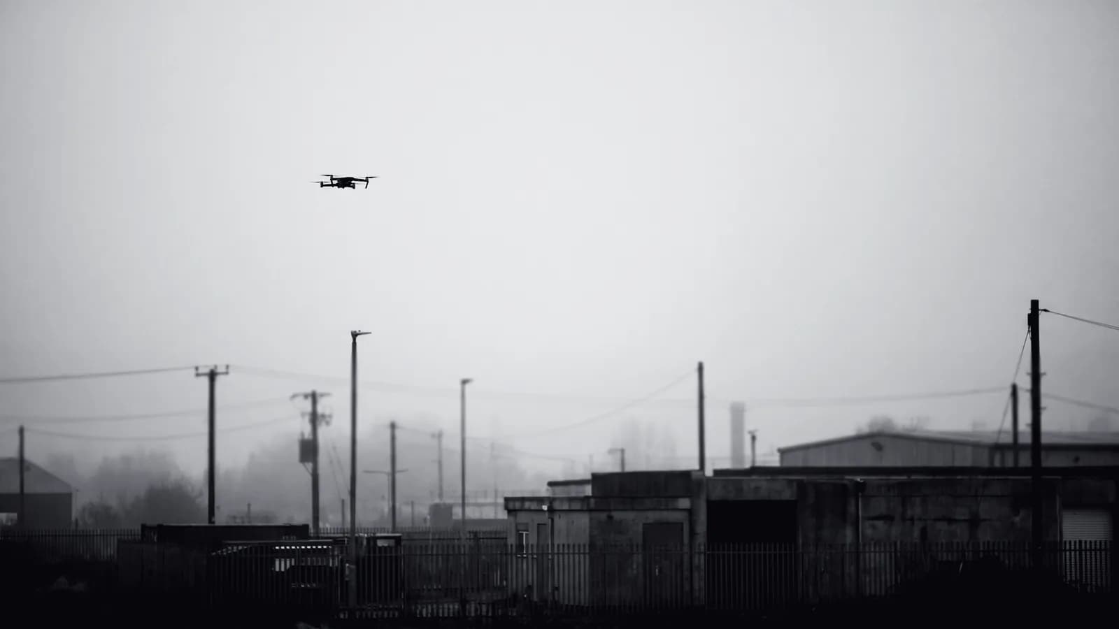 Illustrative frame: a small drone in flight above an industrial perimeter, with computer vision tracking it against a restricted airspace boundary. Shown in black and white, with the annotated regions revealed in colour.