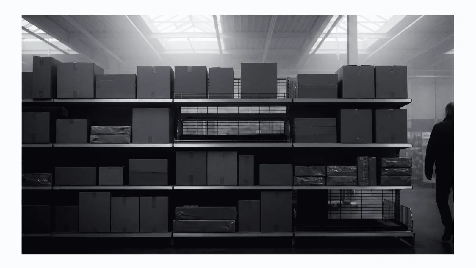 Illustrative frame: a retail shelf bay photographed square on. Rows of plain unbranded packages with two visible gaps where product has sold out. Shown in black and white, with the annotated regions revealed in colour.